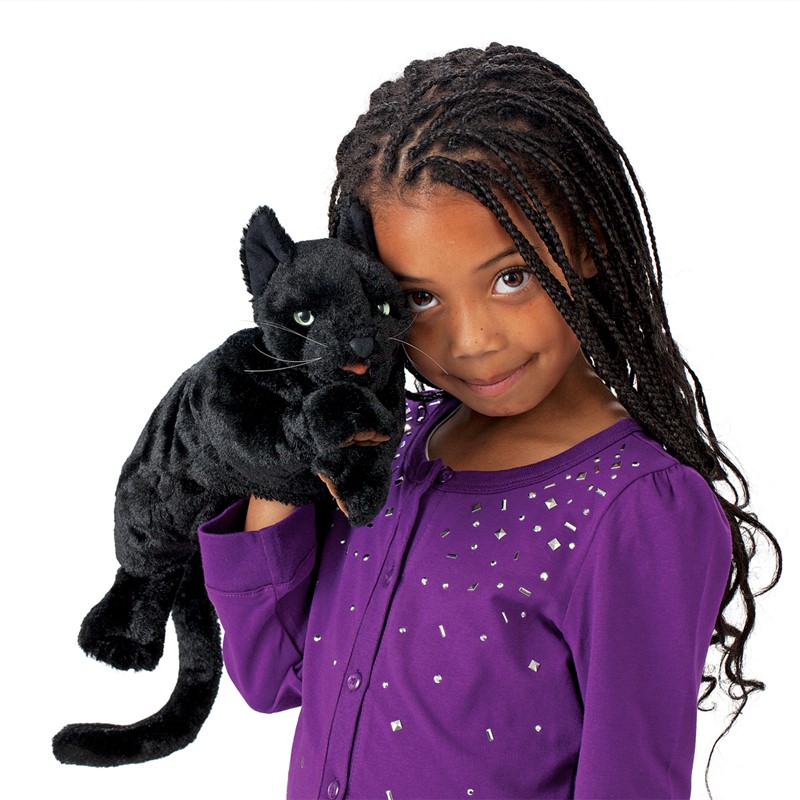 Girl holding up a Folkmanis black cat hand puppet with green eyes and white whiskers