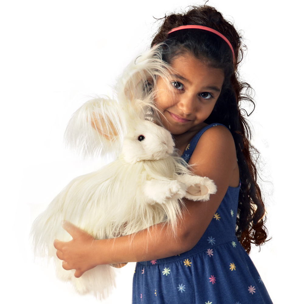 Girl holding a Folkmanis Angora rabbit hand puppet with white long fur and long ears in her arms, front view