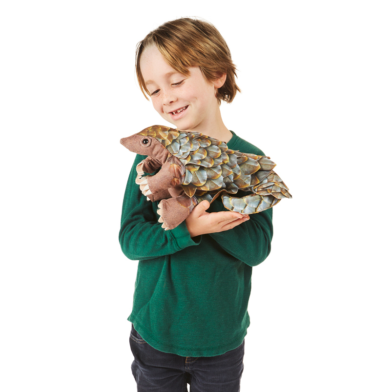 Boy holding a Folkmanis pangolin hand puppet with detailed brown and grey scales, side view