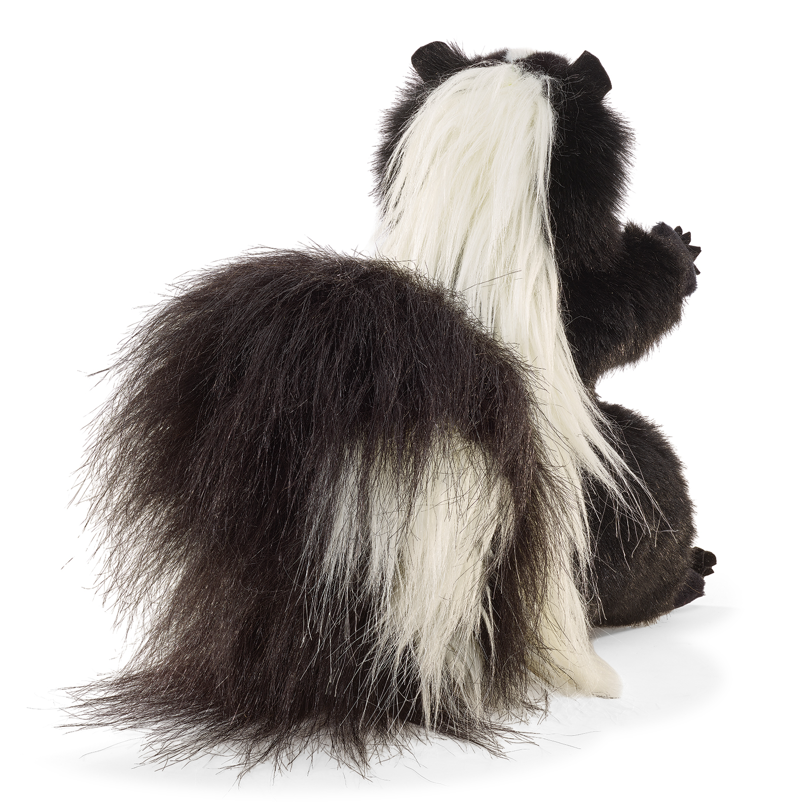 Folkmanis standing skunk hand puppet seen from behind, the broad white stripe running over its back and tail.