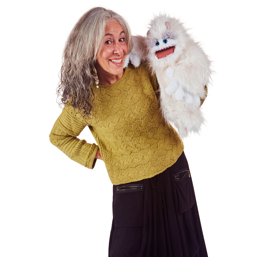 Woman operating the white-furred Folkmanis Yeti hand puppet with blue eyes and a movable mouth on her right hand