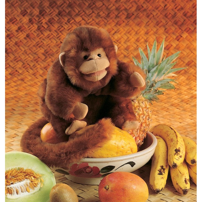Folkmanis brown plush monkey hand puppet sitting in a fruit bowl and holding a pineapple in one hand