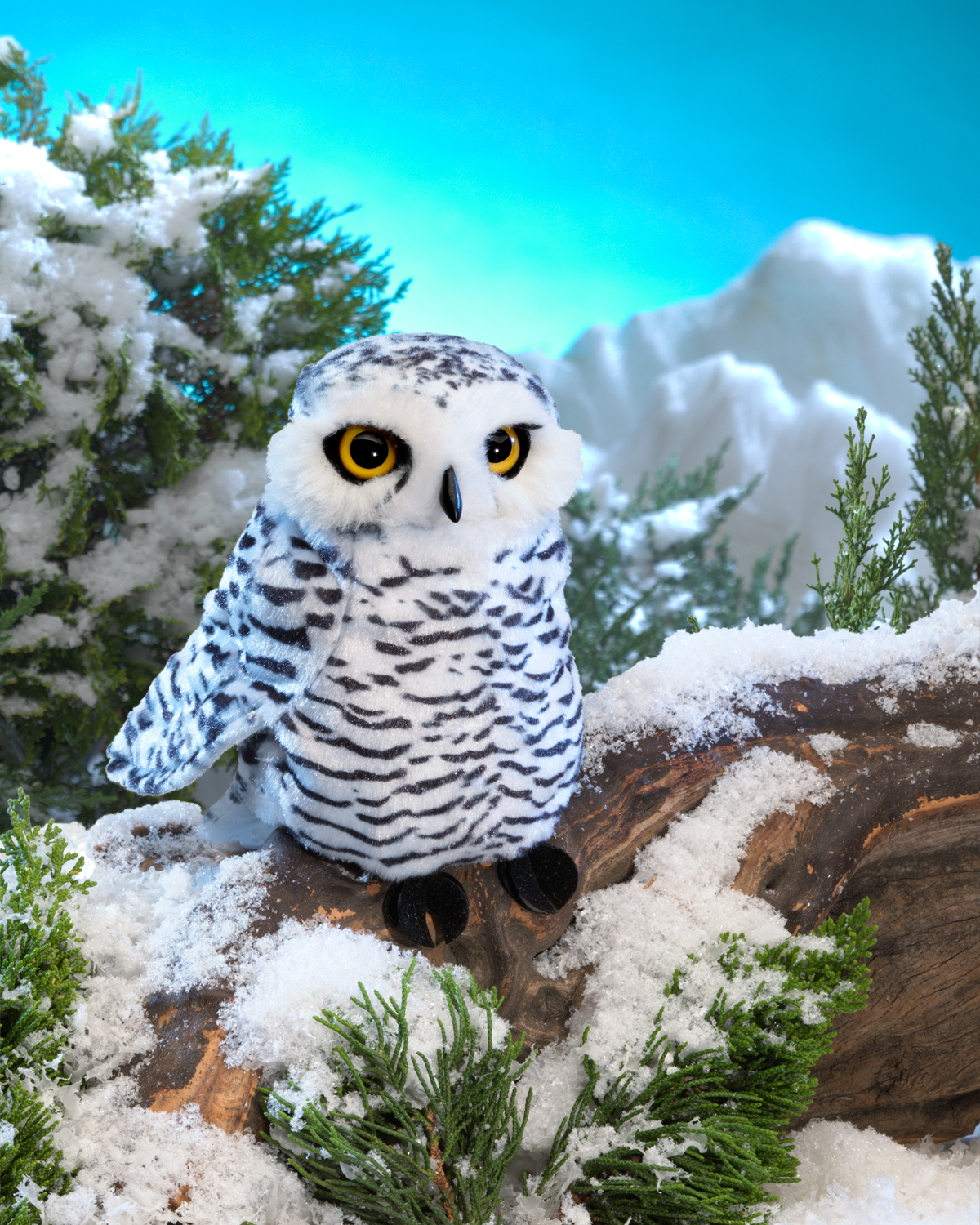 Folkmanis small snowy owl hand puppet, white with dark stripe patterns and yellow eyes, sitting on a snow-covered branch