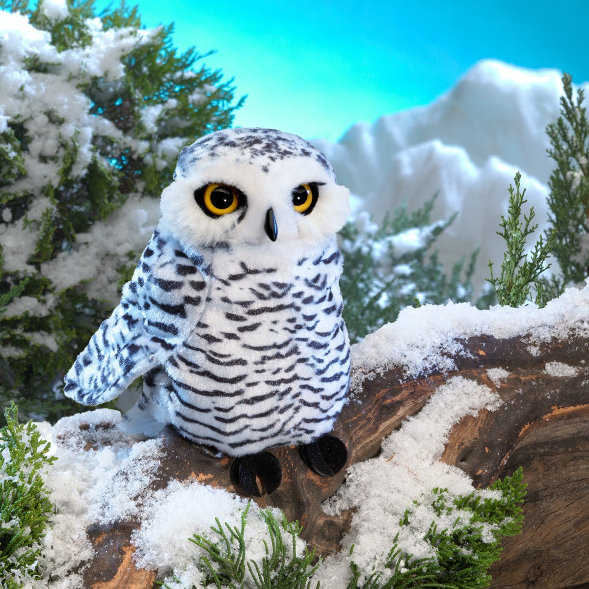 Folkmanis small snowy owl hand puppet, white with dark stripe patterns and yellow eyes, sitting on a snow-covered branch