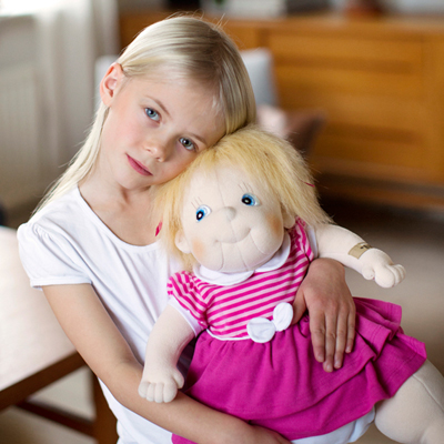 Child hugging the Rubens Barn Original doll Ida with blond hair