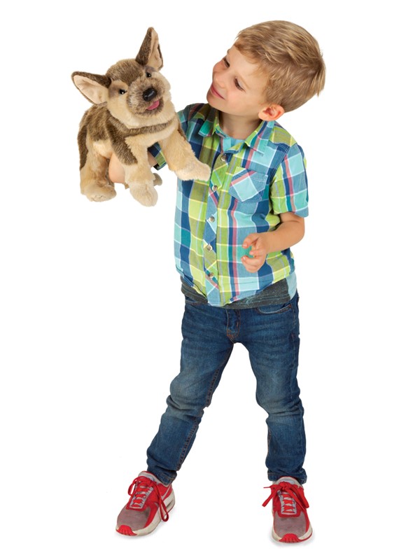 Boy holding a Folkmanis German Shepherd puppy hand puppet with brown fur and tongue sticking out up in the air