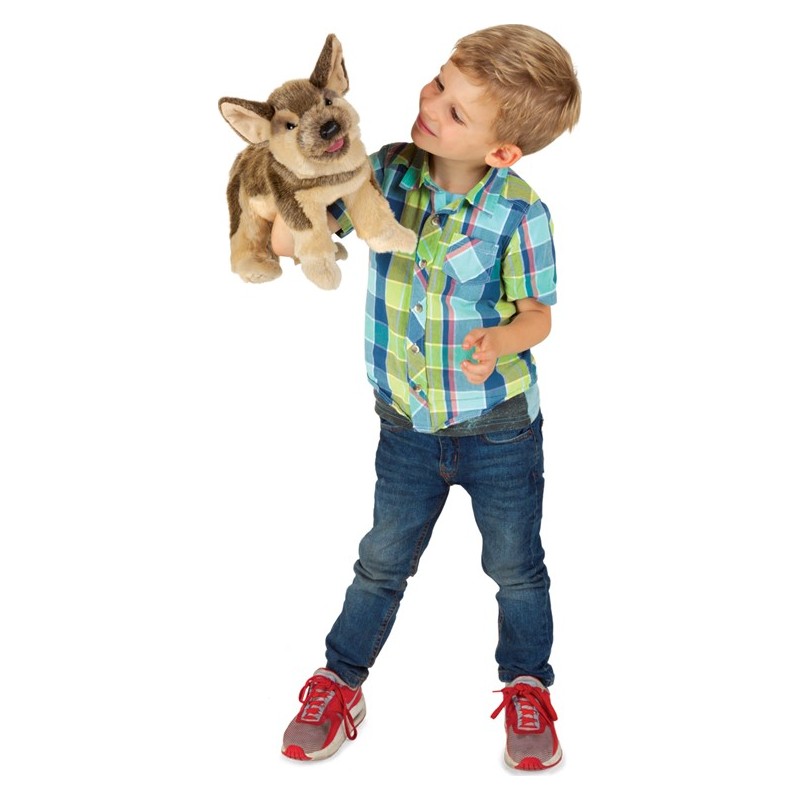 Boy holding a Folkmanis German Shepherd puppy hand puppet with brown fur and tongue sticking out up in the air