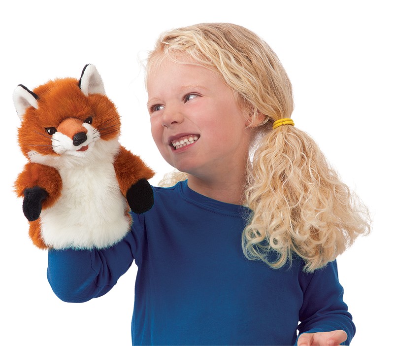 Girl smiling while holding up the Folkmanis Little Fox hand puppet with red-brown fur and white belly