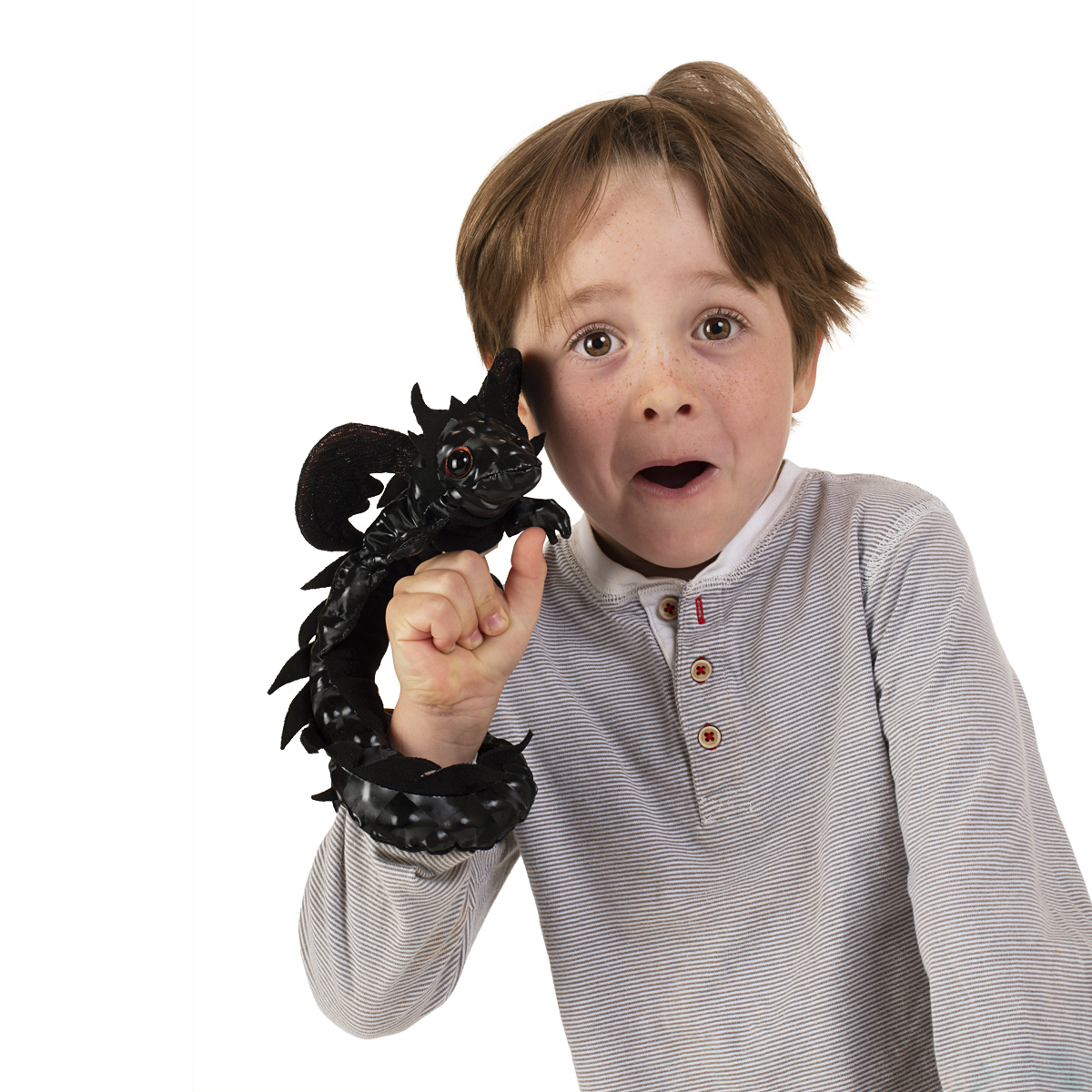 Boy holding a black Folkmanis dragon finger puppet on his outstretched index finger, with the dragon's tail coiling around his wrist