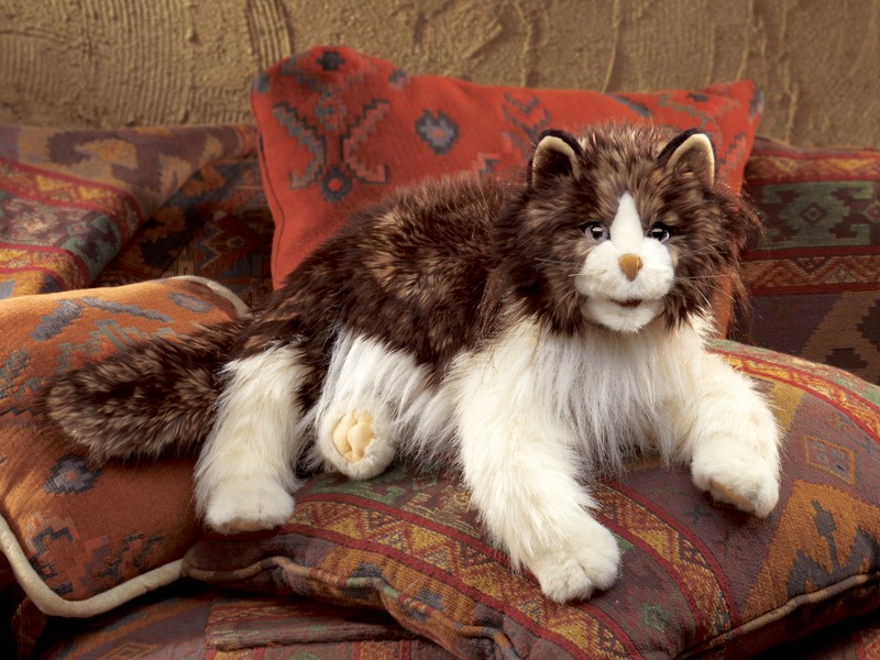 Folkmanis hand puppet fluffy cat with brown-and-white long fur, lying on patterned cushions, side view