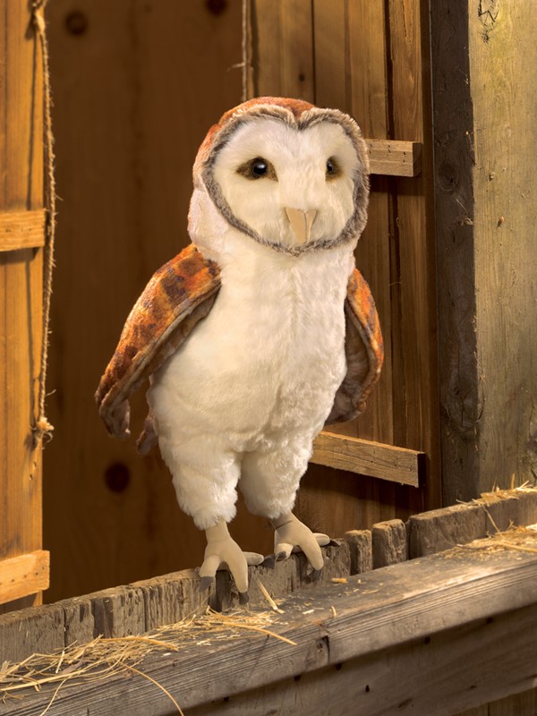 Folkmanis barn owl hand puppet with white belly plumage and rust-brown wings, standing on a wooden beam in a barn