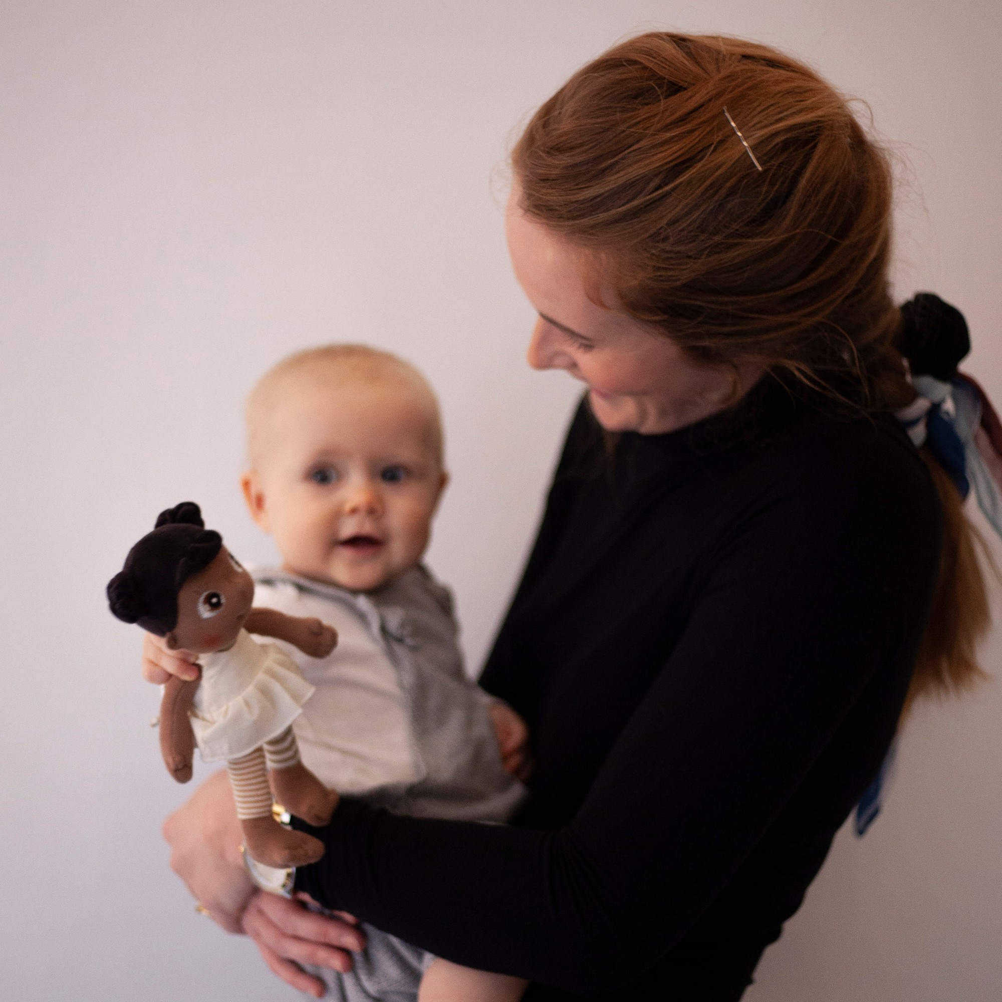 Woman showing a baby the Rubens EcoBuds mini doll Flora