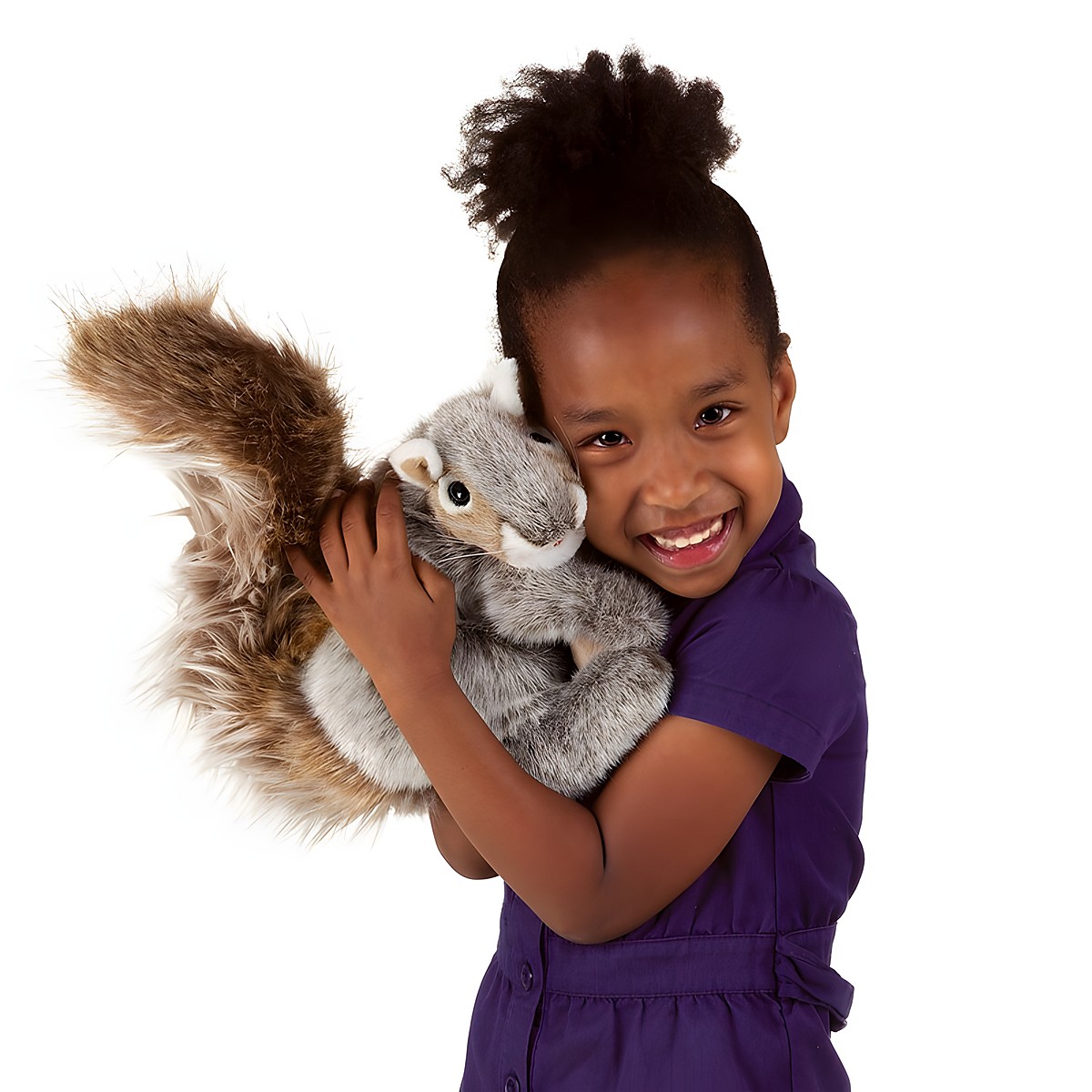 Girl smiling and holding a Folkmanis grey squirrel hand puppet with a bushy brown tail against her cheek