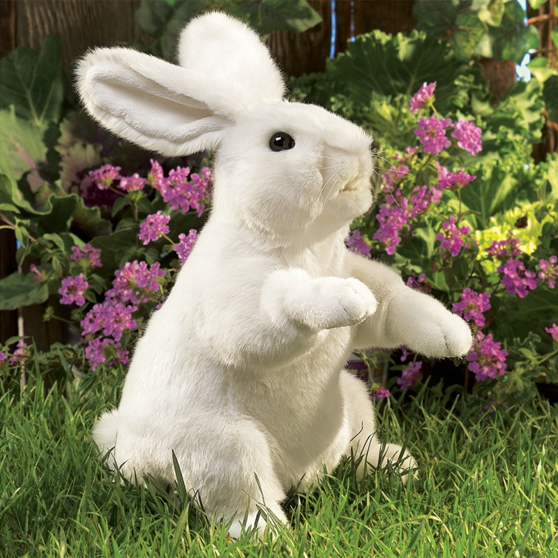 Folkmanis hand puppet white rabbit in upright pose on grass, in front of purple flowers, side view