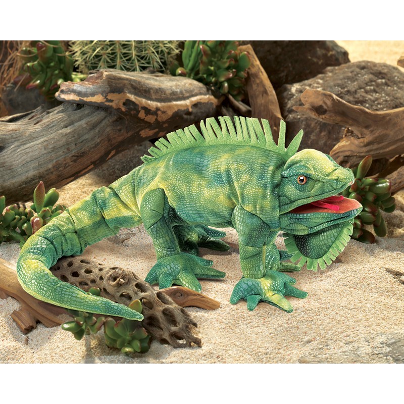 Folkmanis iguana hand puppet in green with detailed scale texture, dorsal crest and open mouth, displayed on sand