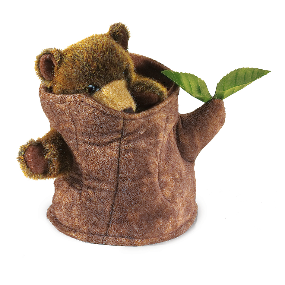 Folkmanis hand puppet bear in a brown plush tree stump, bear peeks out with paws and golden snout, green leaves on the side