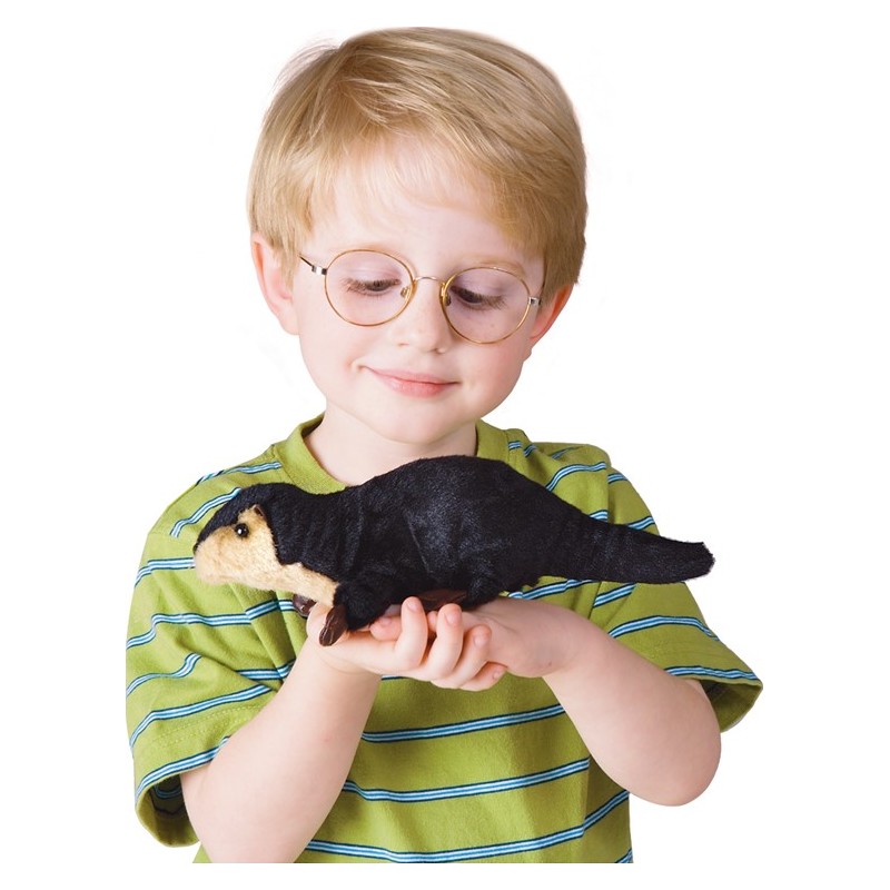 Boy with glasses holding the Folkmanis mini river otter finger puppet in his open hand, smiling down at it