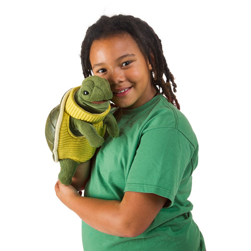 Folkmanis turtle hand puppet wearing a yellow turtleneck sweater, held by a smiling child, side view