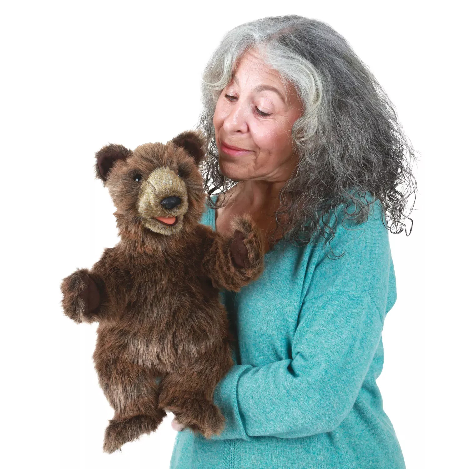 Woman with grey hair holding the Folkmanis bear cub hand puppet with movable mouth in her arms, front view