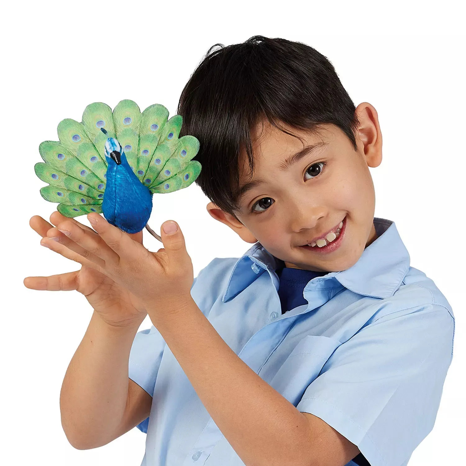 Folkmanis mini peacock finger puppet with fanned green-blue tail feathers on the finger of a smiling boy