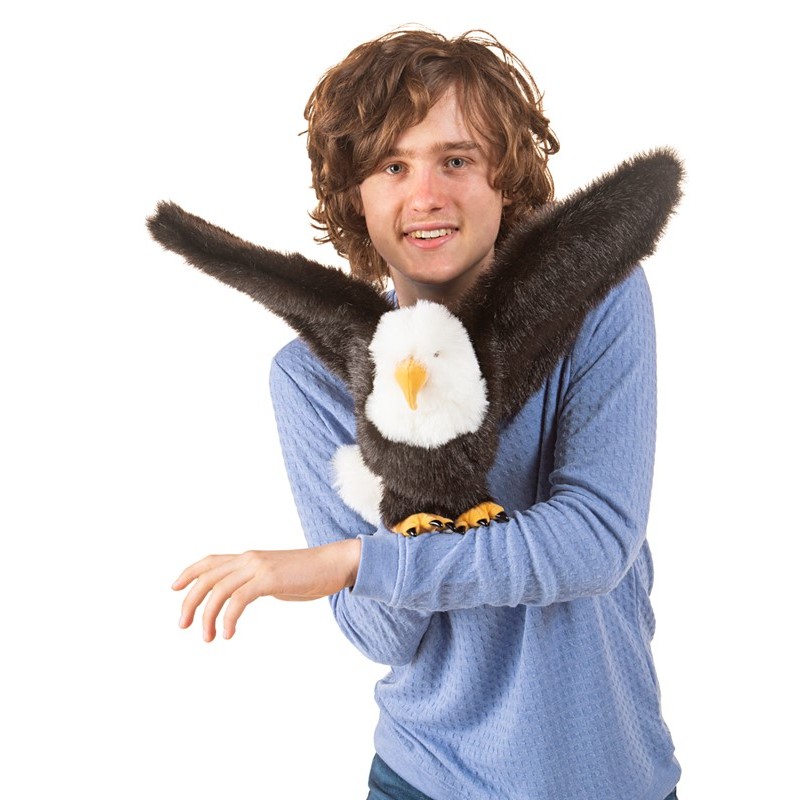 Folkmanis bald eagle hand puppet with spread wings, held on the arm of a teenager, front view