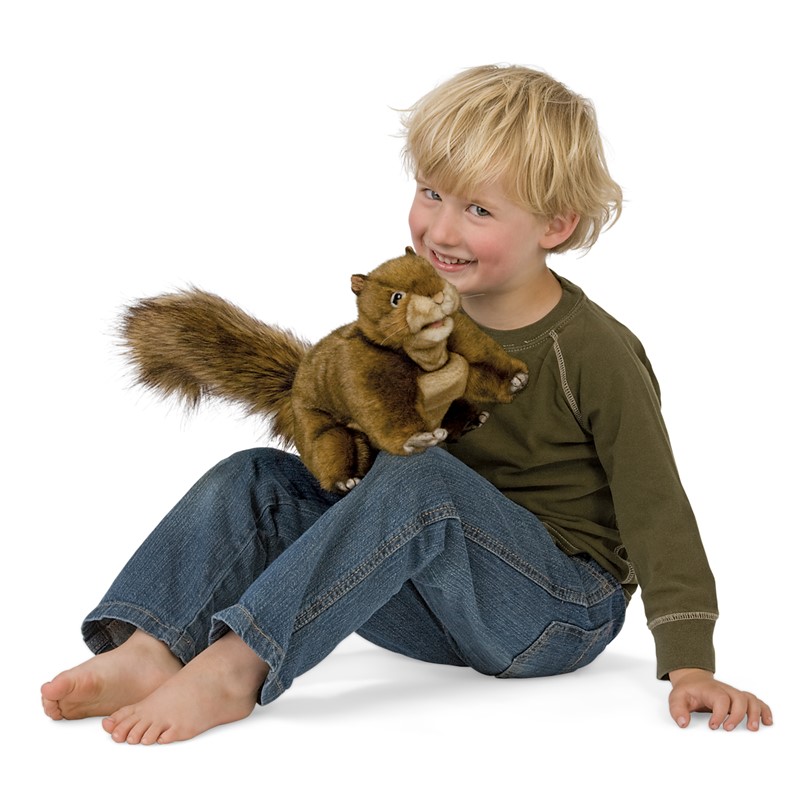 Laughing boy holding a Folkmanis red-brown squirrel hand puppet with a bushy tail in his hands