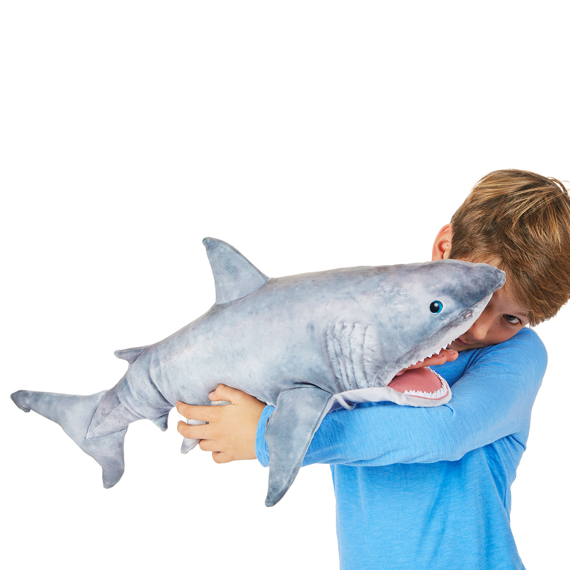 Boy holding a large Folkmanis great white shark hand puppet with open mouth and white teeth in both arms