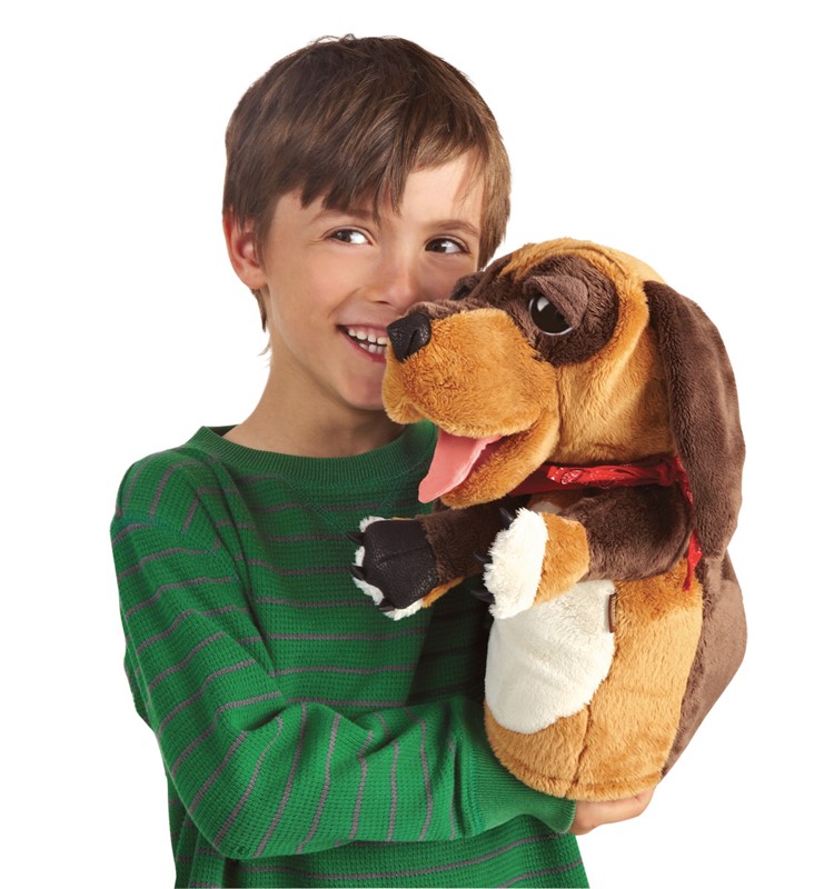 Laughing boy holding a Folkmanis dog hand puppet with an open mouth, stuck-out tongue, and red collar in his arms
