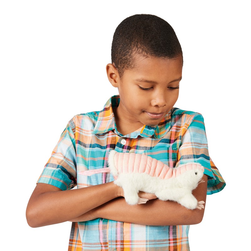 Boy holds a Folkmanis pink fairy armadillo hand puppet with white fur to his chest, smiling down at it