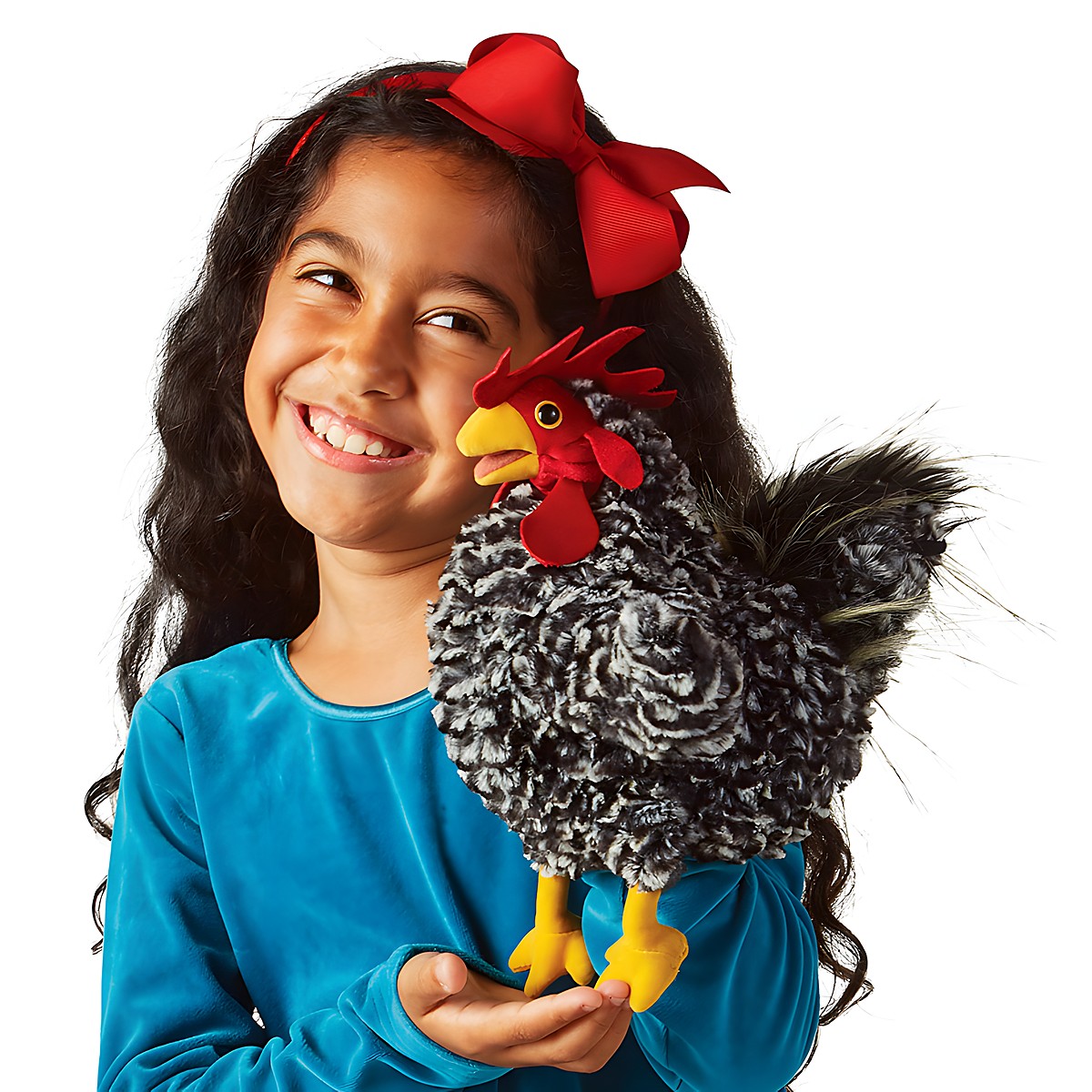 Girl holding a Folkmanis rooster hand puppet with black-and-white curly feathers, a red comb, and yellow legs