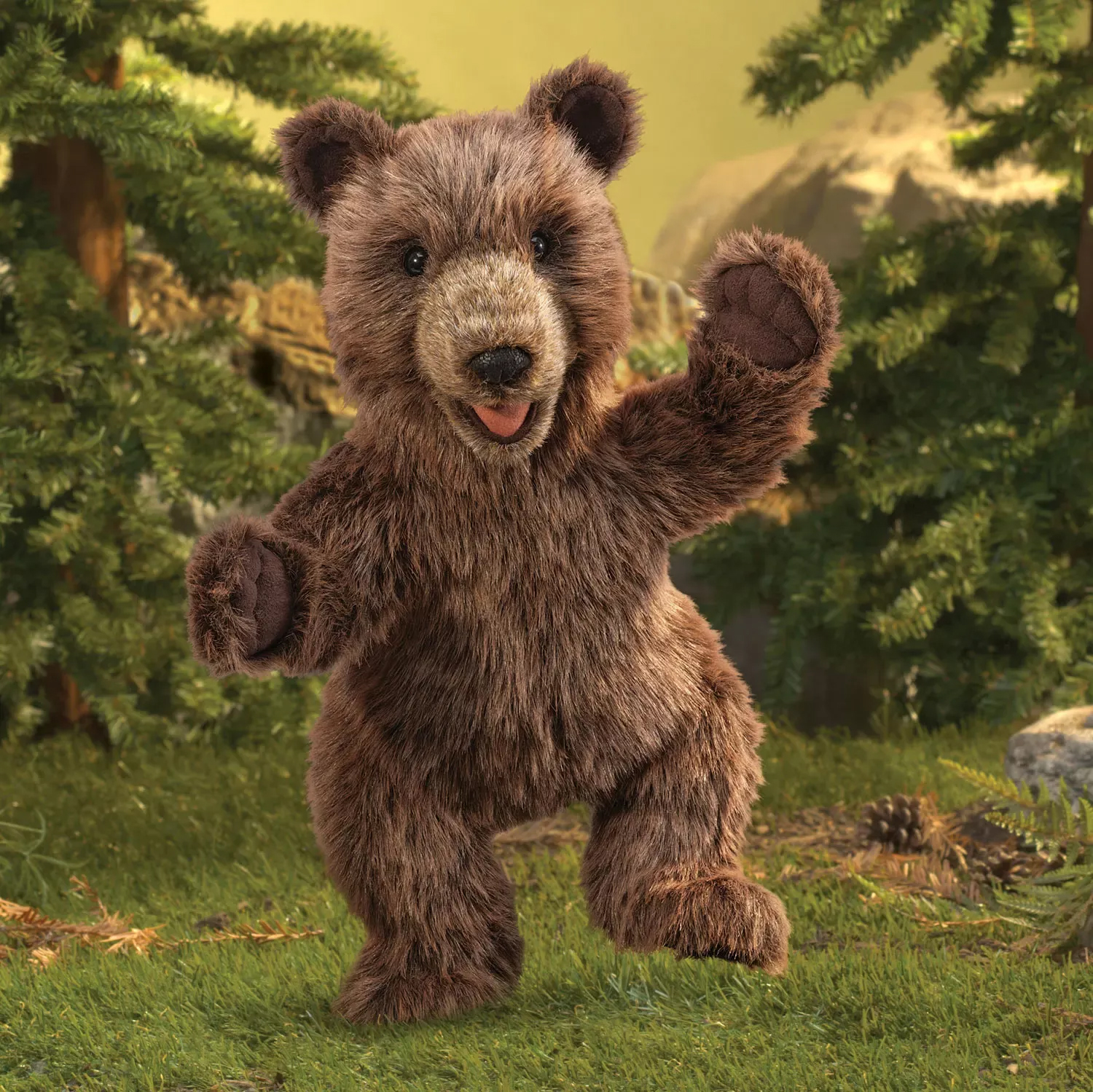 Folkmanis brown plush bear cub hand puppet standing with open mouth and raised paw against a forest backdrop