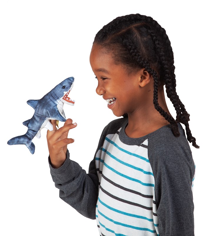 Child laughing while wearing a Folkmanis mini shark finger puppet in blue-grey with open mouth on their index finger