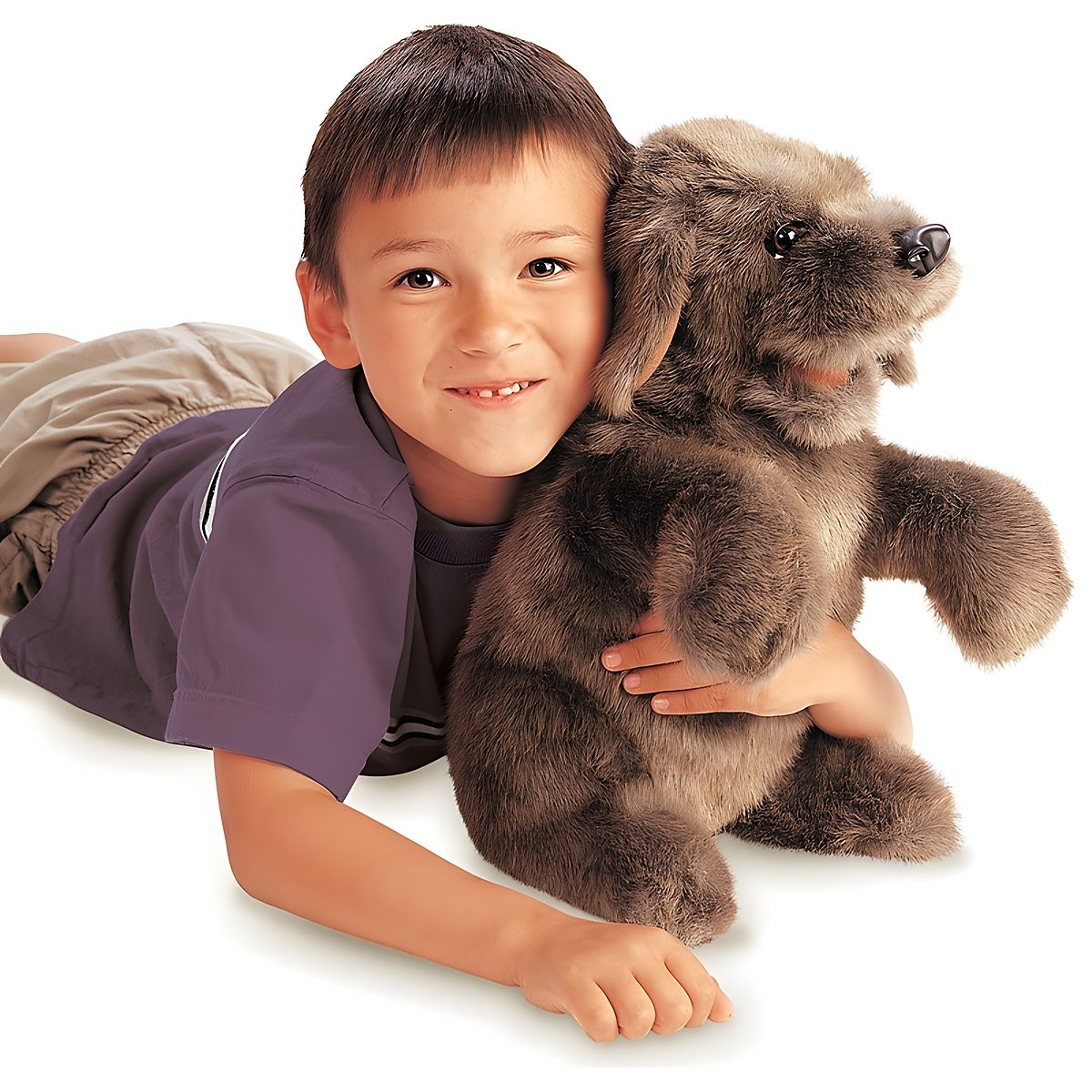 Boy cuddling the grey-brown Folkmanis dog hand puppet in its sitting pose, close-up.