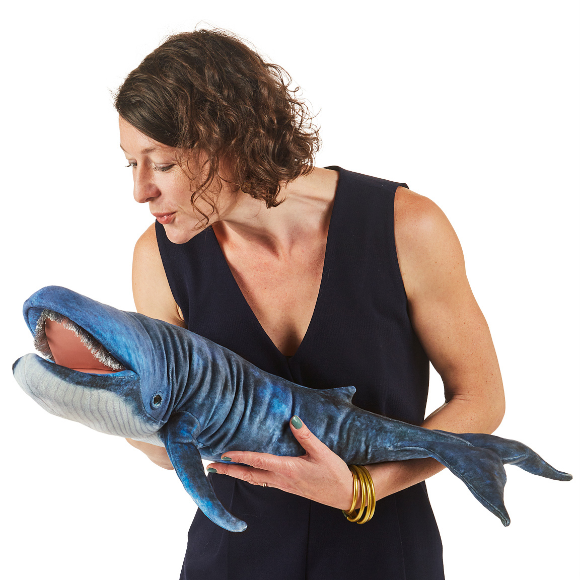 Folkmanis blue whale hand puppet in blue-grey with open mouth, held in a woman's arms for size comparison