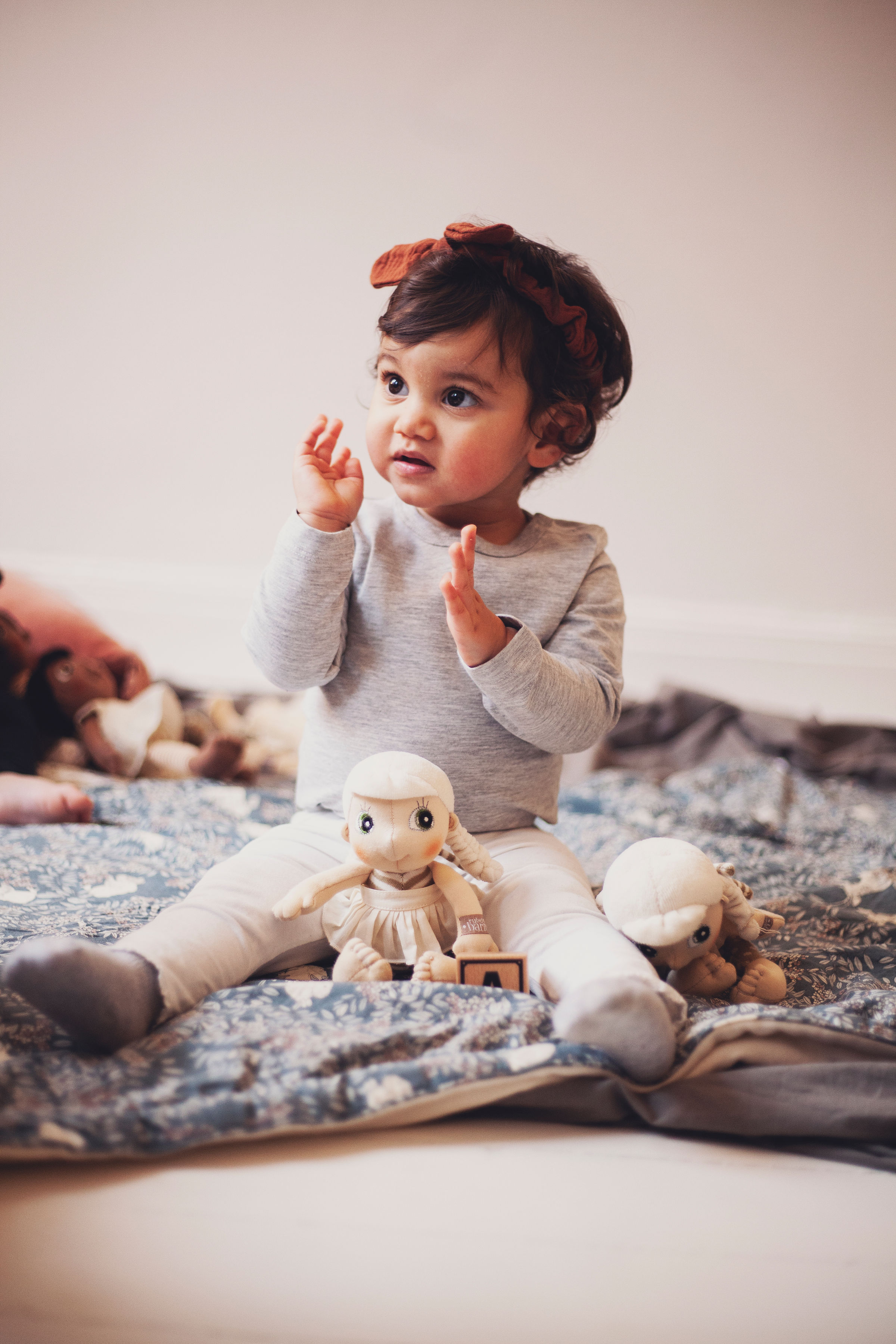 Toddler playing with the Rubens EcoBuds mini doll Lily on a blanket