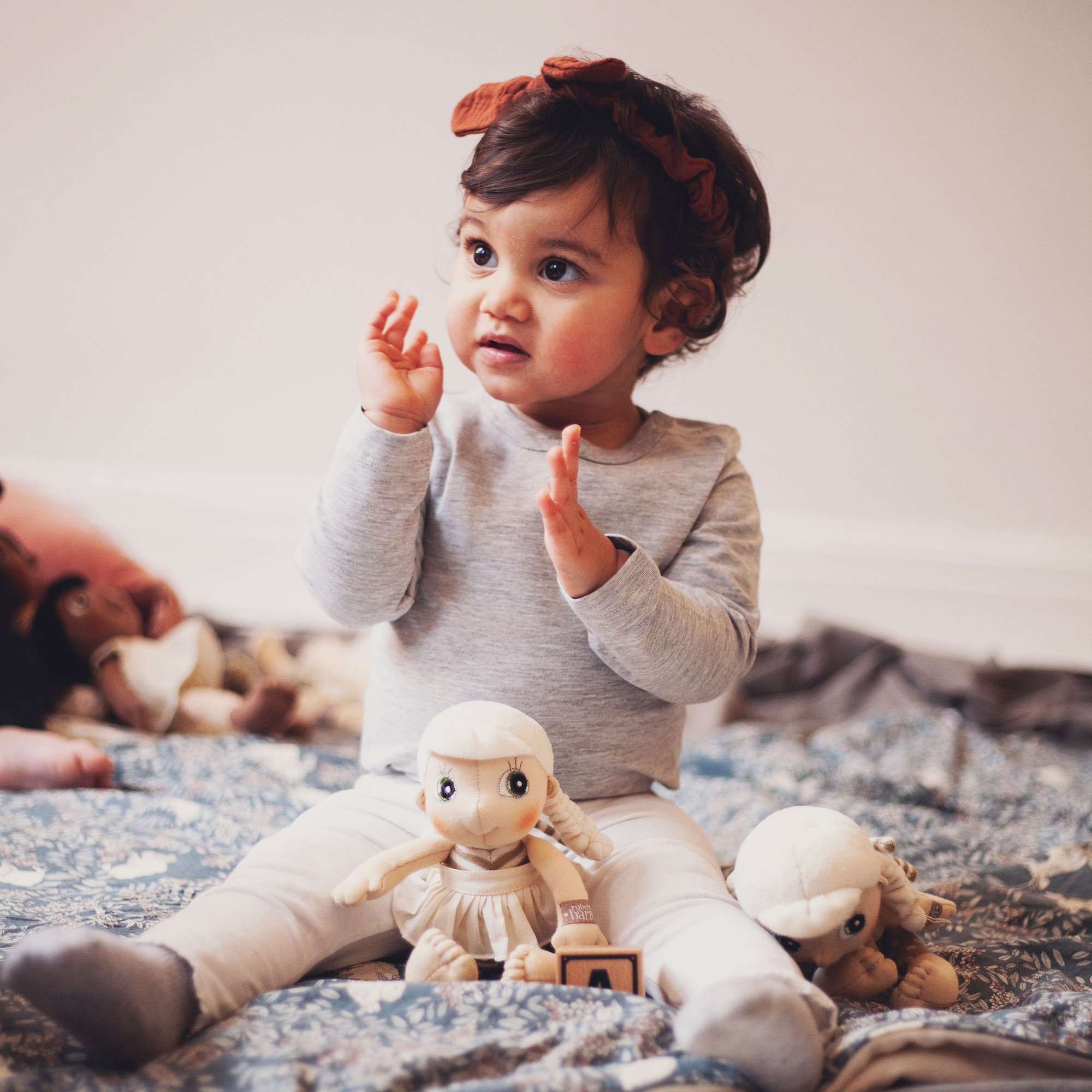 Toddler playing with the Rubens EcoBuds mini doll Lily on a blanket