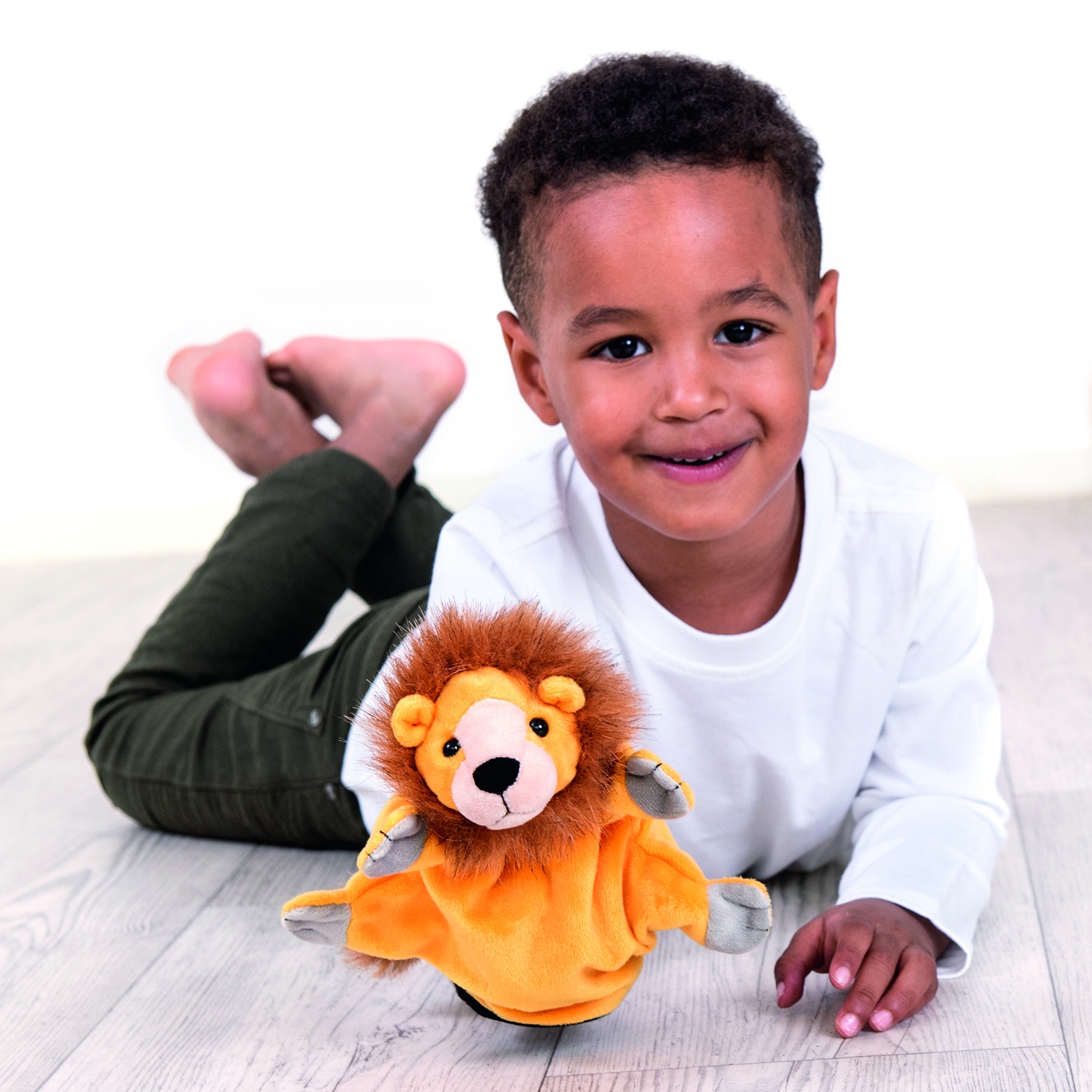 Boy lying on the floor with the Beleduc hand puppet lion, usage example