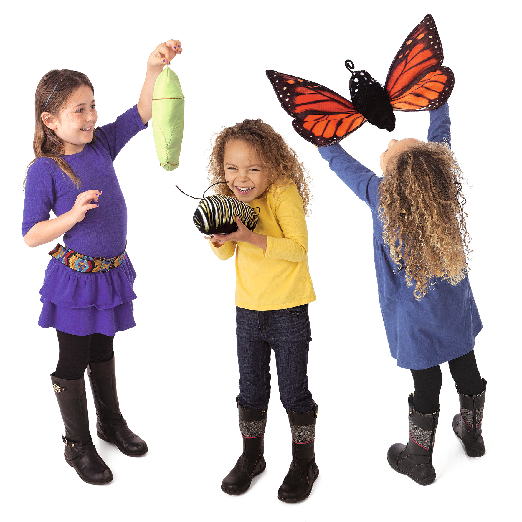 Three girls playing with the Folkmanis Monarch butterfly metamorphosis hand puppet set: chrysalis, caterpillar, and orange-and-black Monarch butterfly