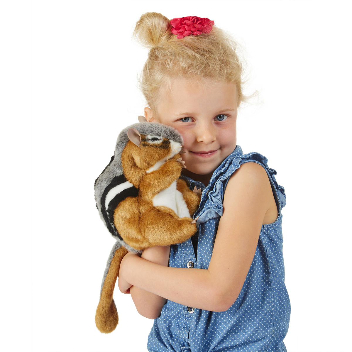 Girl holding a Folkmanis chipmunk hand puppet with brown-and-black stripes and a grey back against her cheek