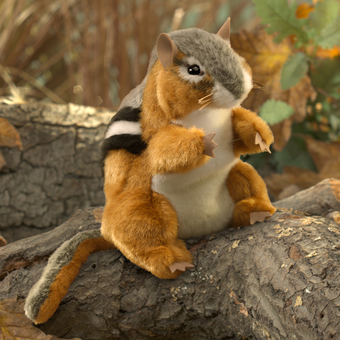 Folkmanis chipmunk hand puppet with rust-brown fur and characteristic black-and-white back stripes, sitting upright on a log