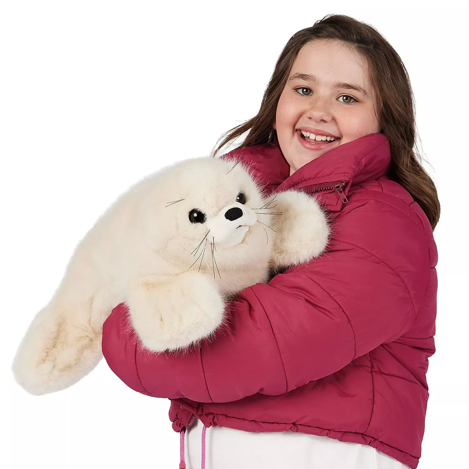 Girl in a pink jacket hugging the Folkmanis harp seal pup hand puppet with white plush fur and black button eyes