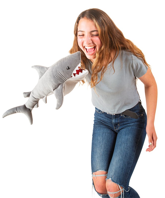 Laughing teenage girl being grabbed at the stomach by a grey Folkmanis shark hand puppet with red teeth