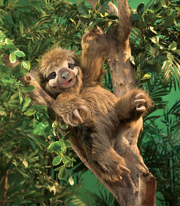 Folkmanis three-toed sloth hand puppet with brown plush fur and characteristic claws clinging to a branch in a jungle setting