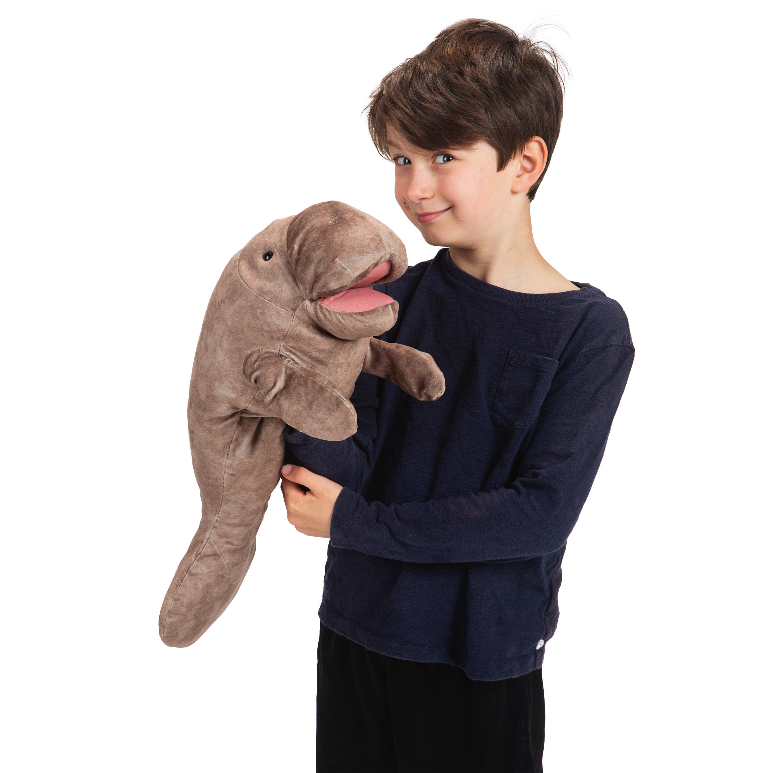 Boy holding a Folkmanis manatee hand puppet made of grey-brown plush with an open pink mouth in his arms
