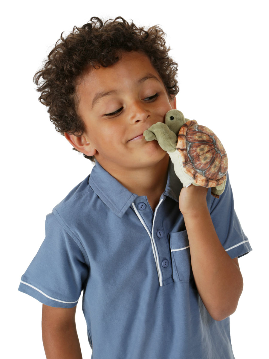 Boy holding a Folkmanis mini tortoise finger puppet with a realistically printed shell up to his face