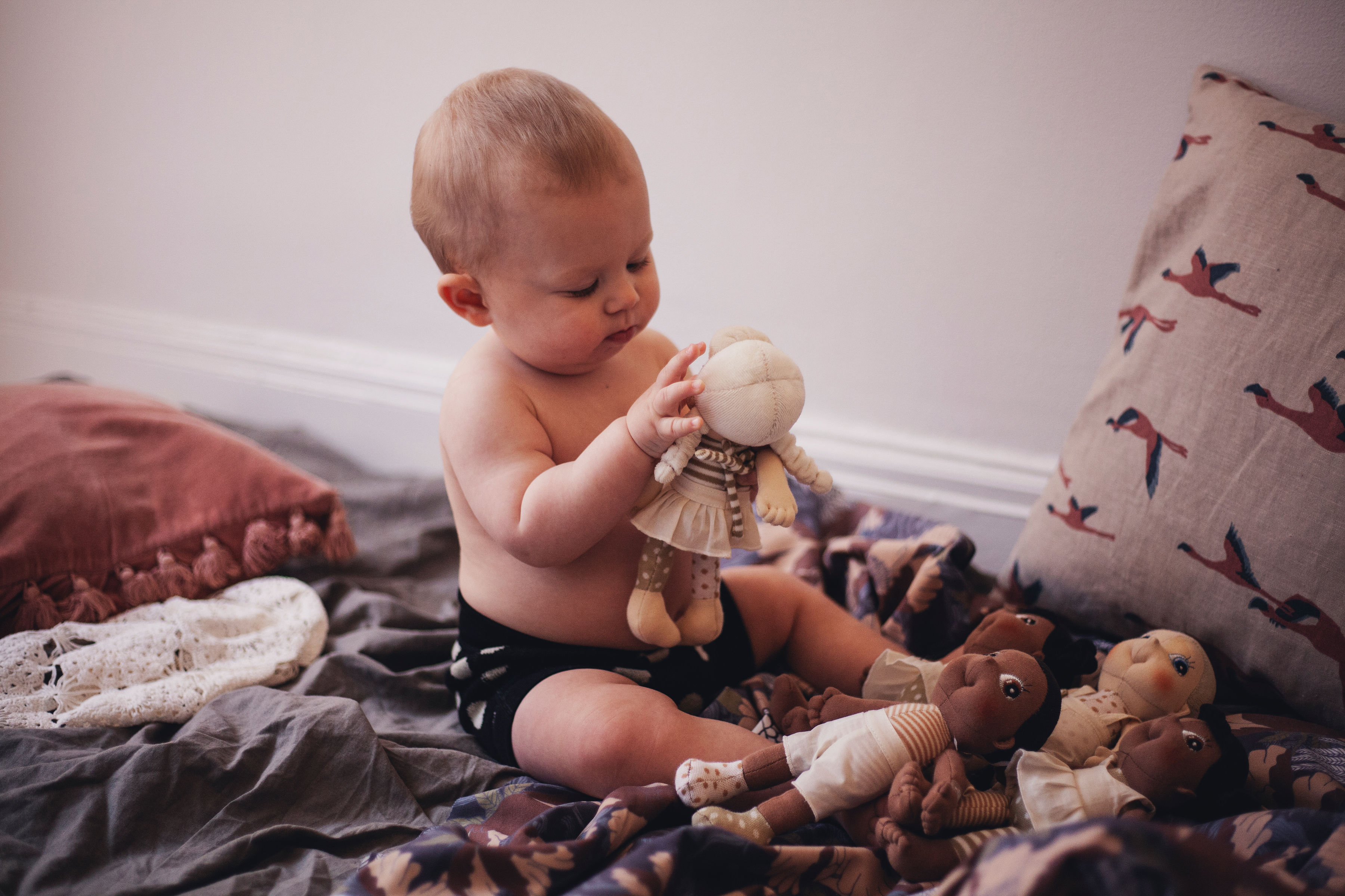 Baby playing with a Rubens EcoBuds mini doll on a blanket
