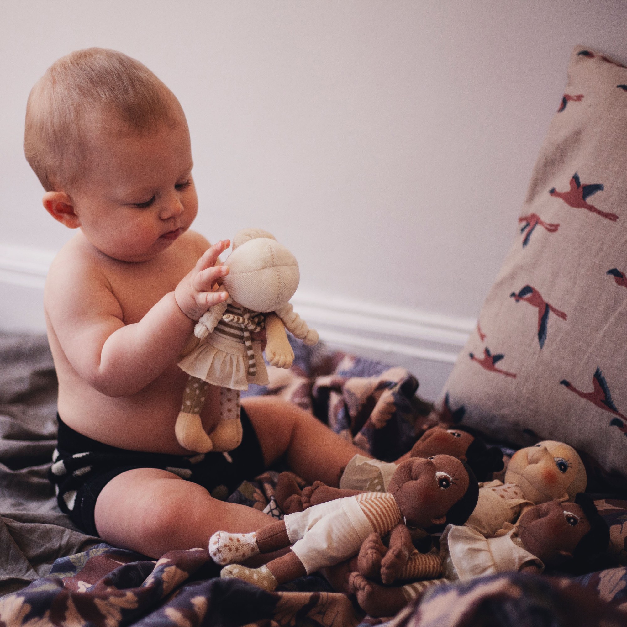 Baby playing with a Rubens EcoBuds mini doll on a blanket