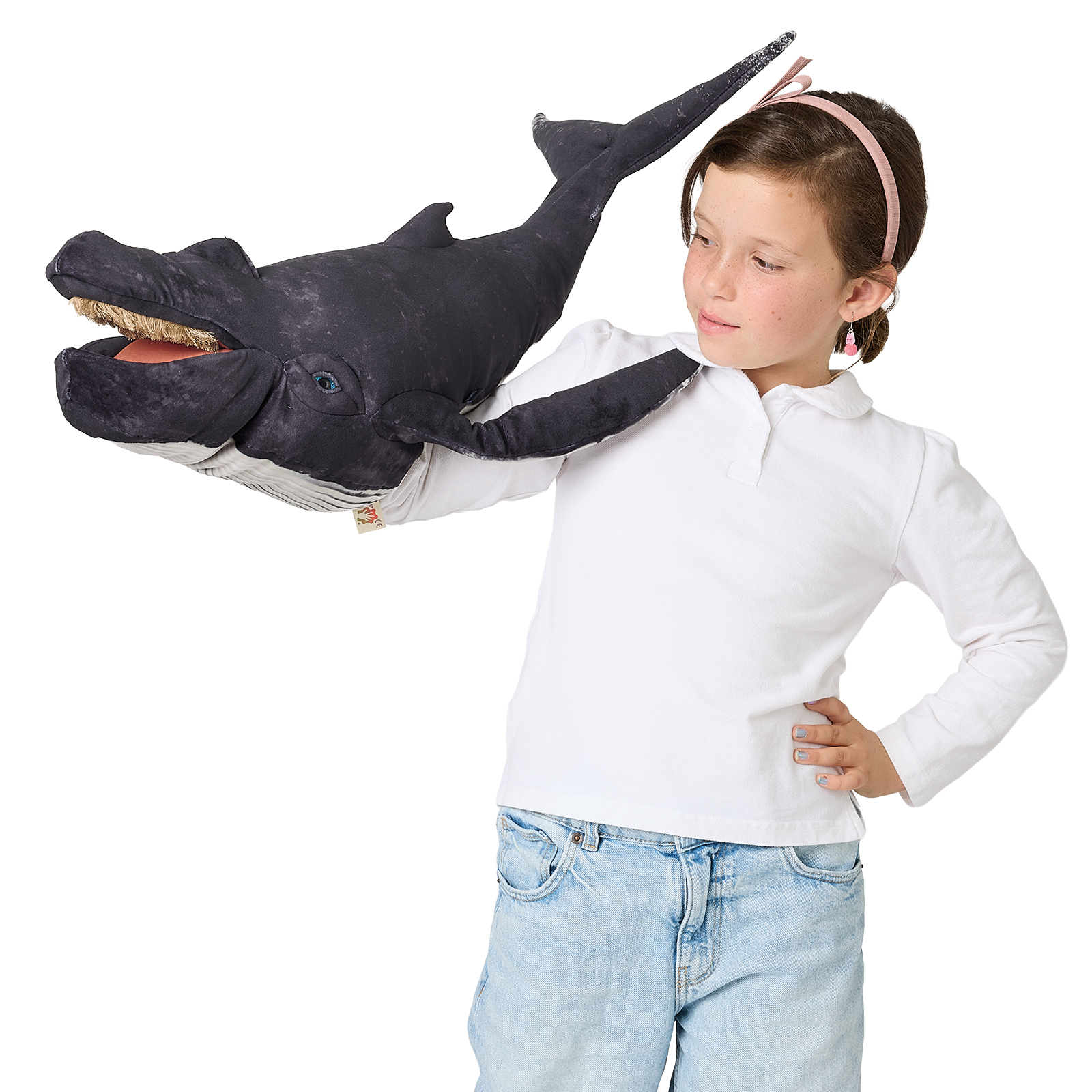 Girl operating a large Folkmanis humpback whale hand puppet with open mouth and dark grey plush body over her outstretched arm