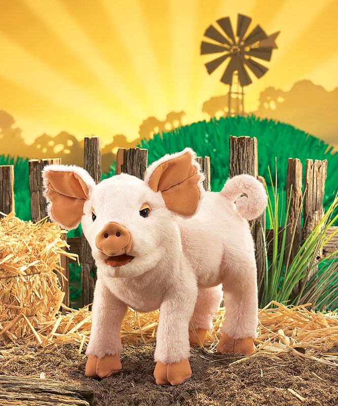 Folkmanis piglet hand puppet in pink, standing with open mouth, in front of hay bales and a farm backdrop