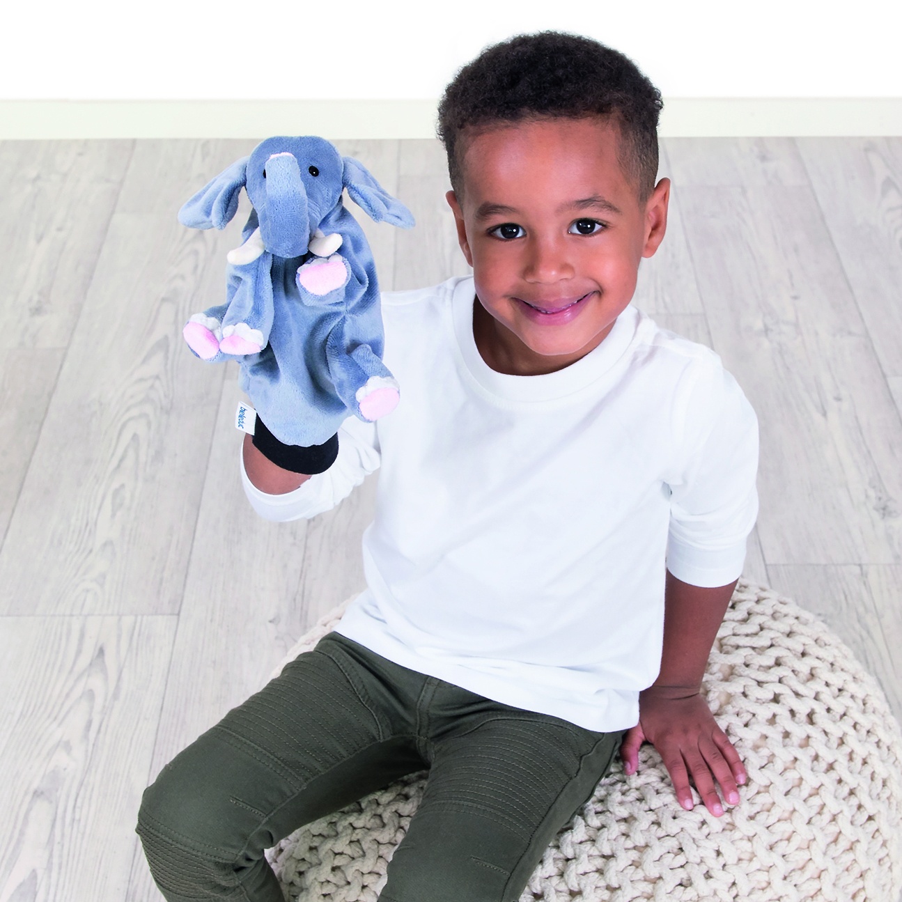 Boy smiling and showing the Beleduc hand puppet elephant on his hand, usage example